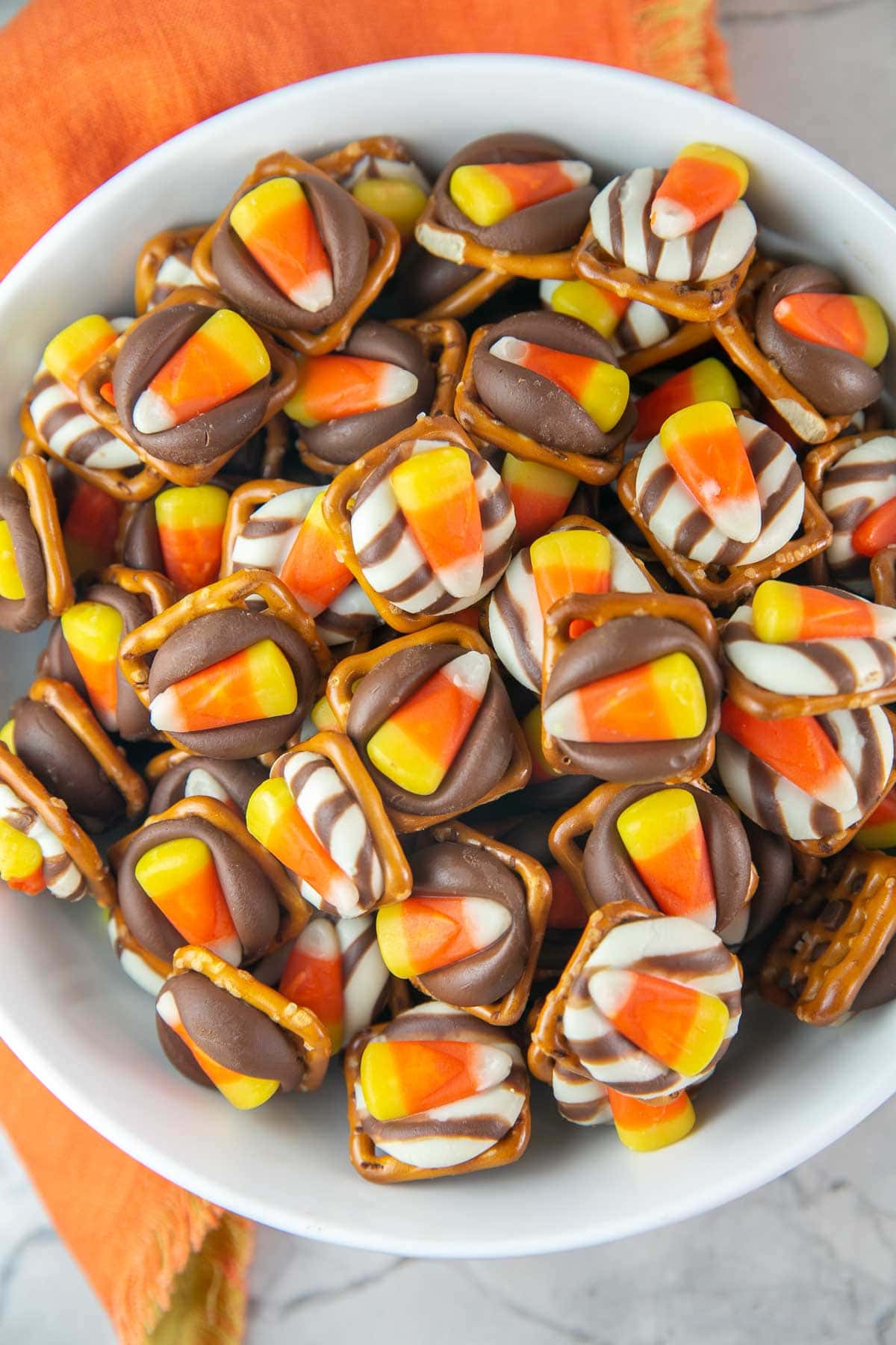 large bowl filled with pretzels covered with a kiss and a piece of candy corn.