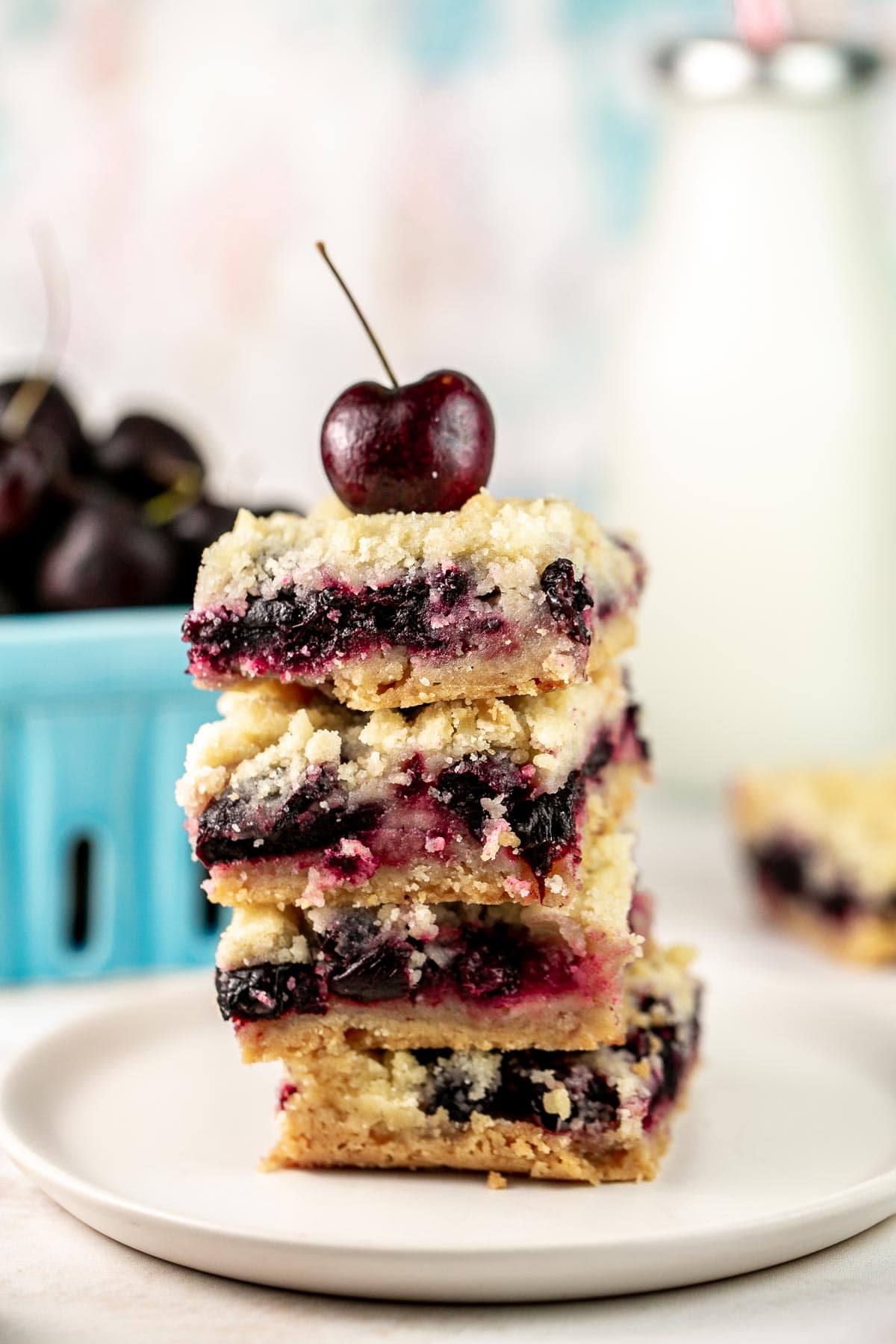 a stack of four cherry pie bars with a fresh cherry on top
