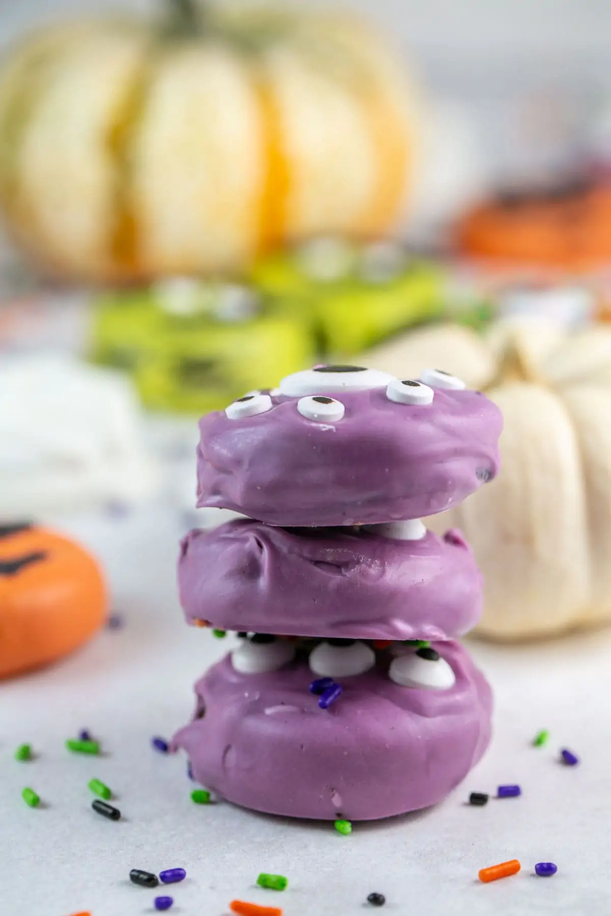 a stack of three Oreos covered in purple candy melts and decorated with candy eyeballs.
