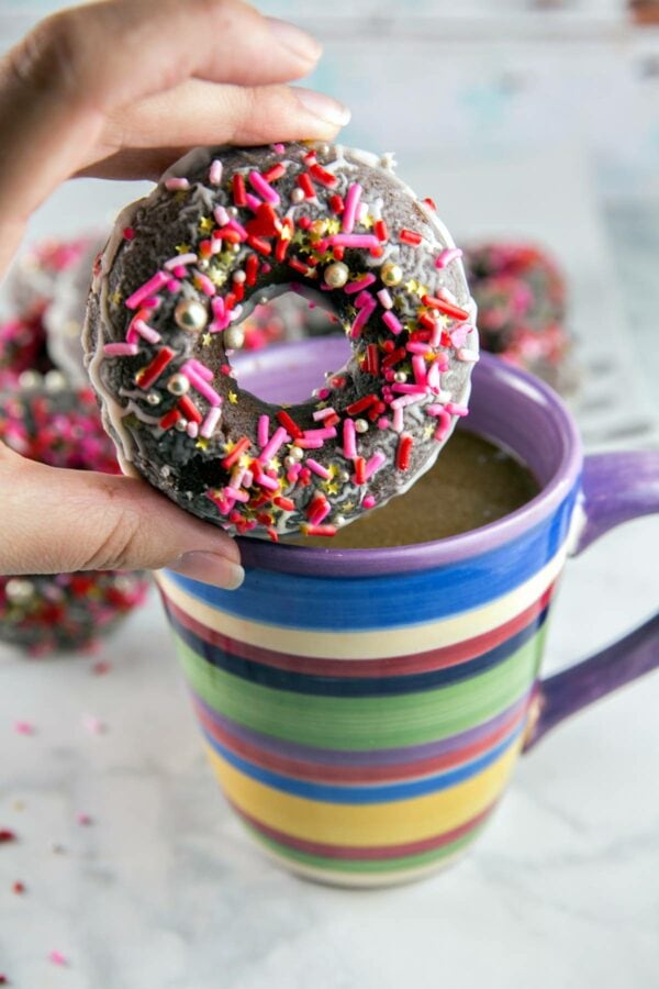 peppermint mocha donut held up in front of a cup of coffee