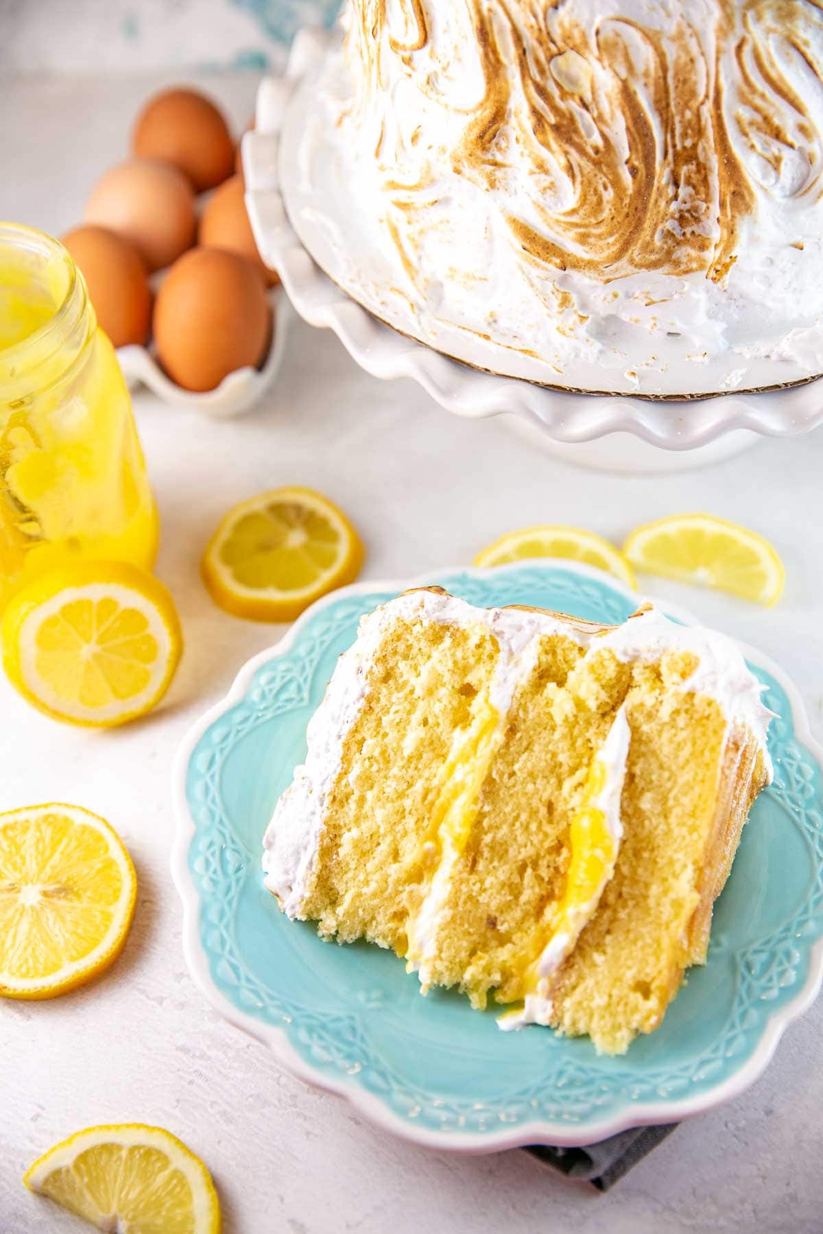 slice of lemon meringue cake on its side with lemon curd filling between cake layers