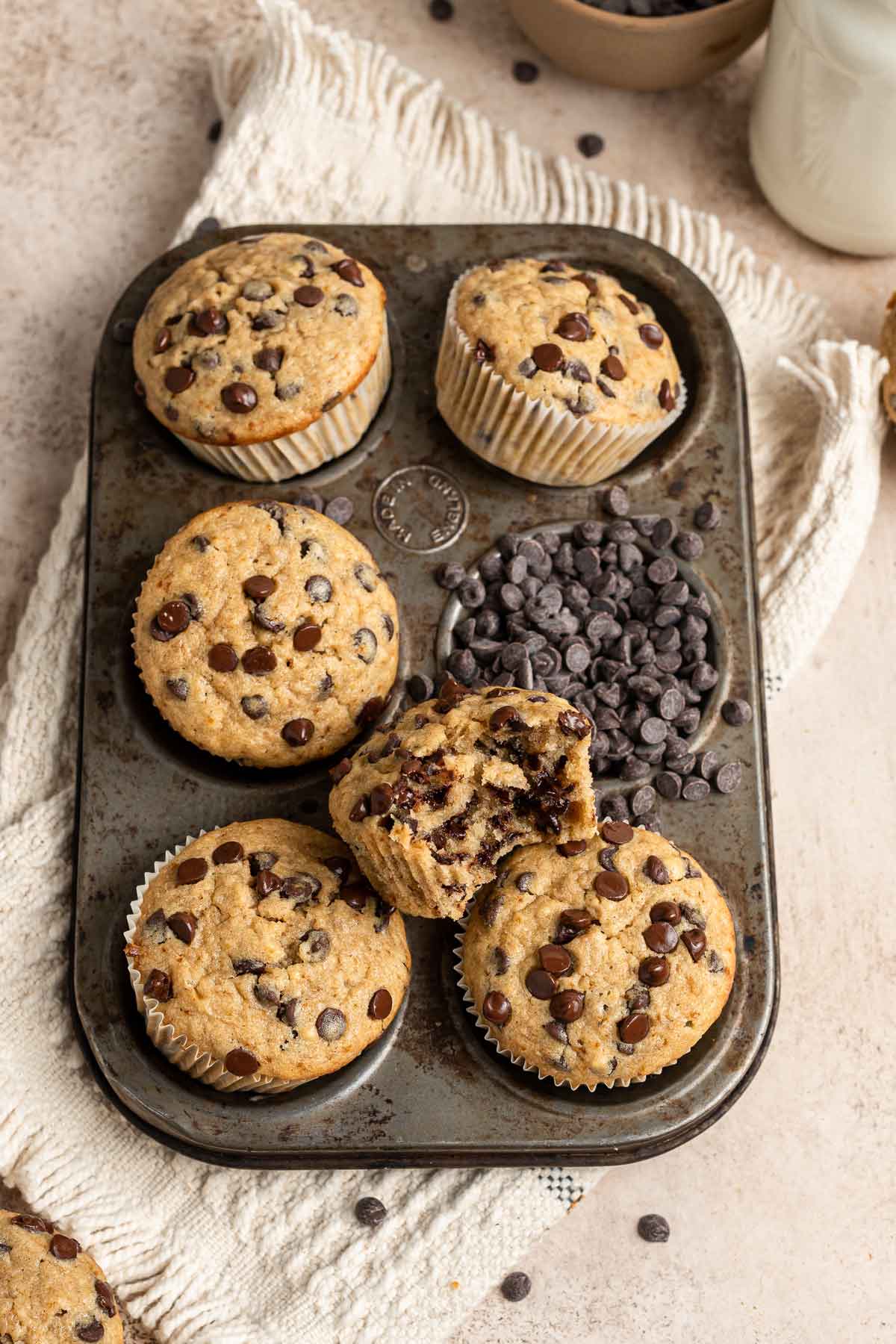 banana bread muffins in a muffin tin with one bite taken out of a muffin