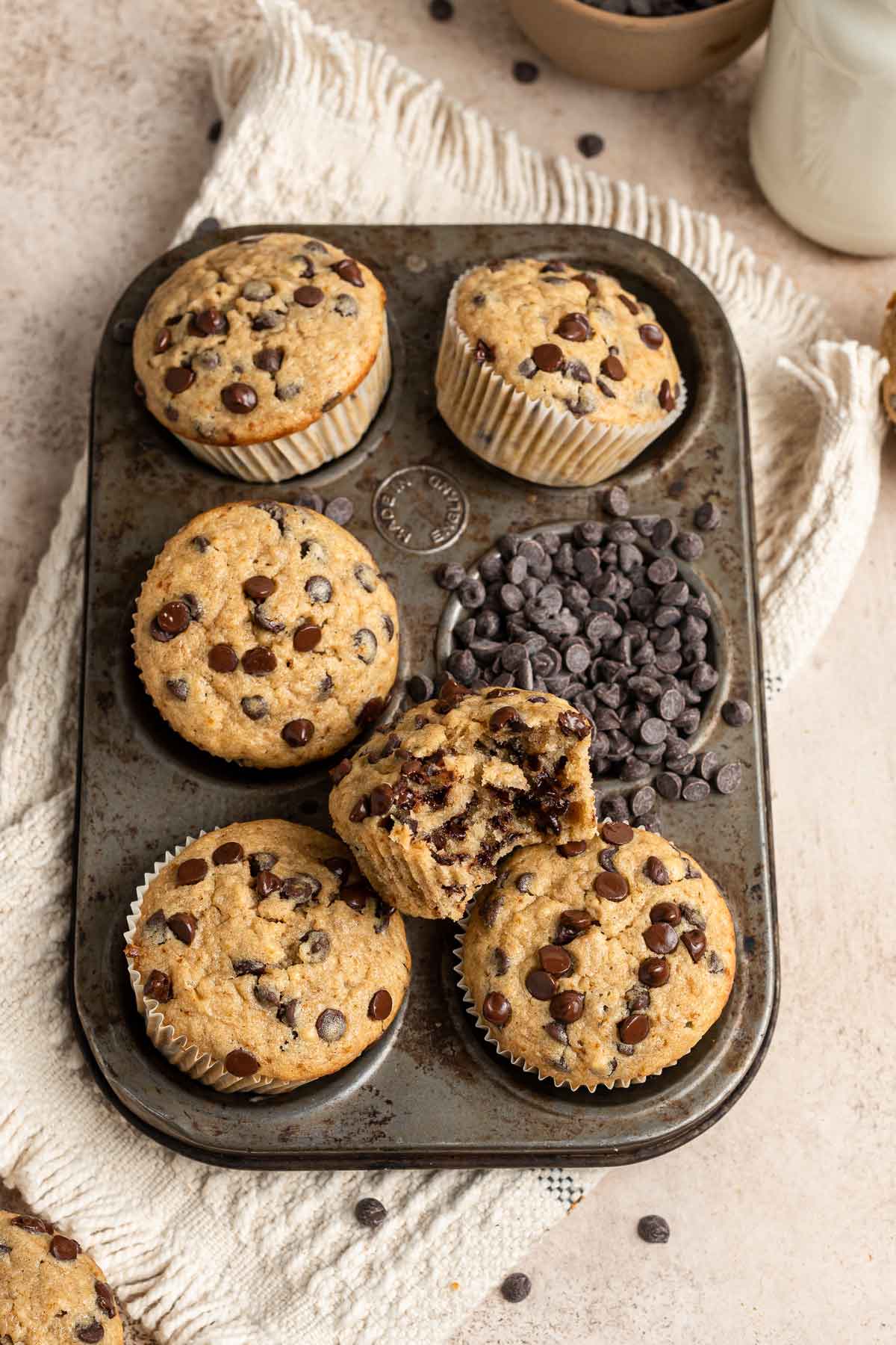 banana bread muffins in a muffin tin with one bite taken out of a muffin.