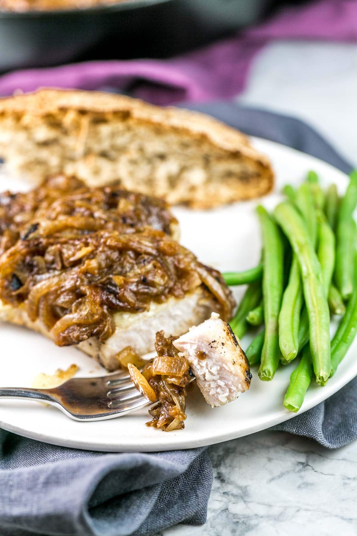 french onion pork chops on a plate next to steamed green beans