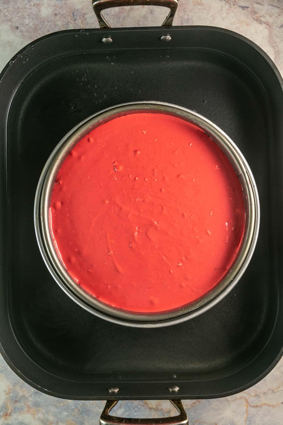 unbaked cheesecake sitting in a water bath