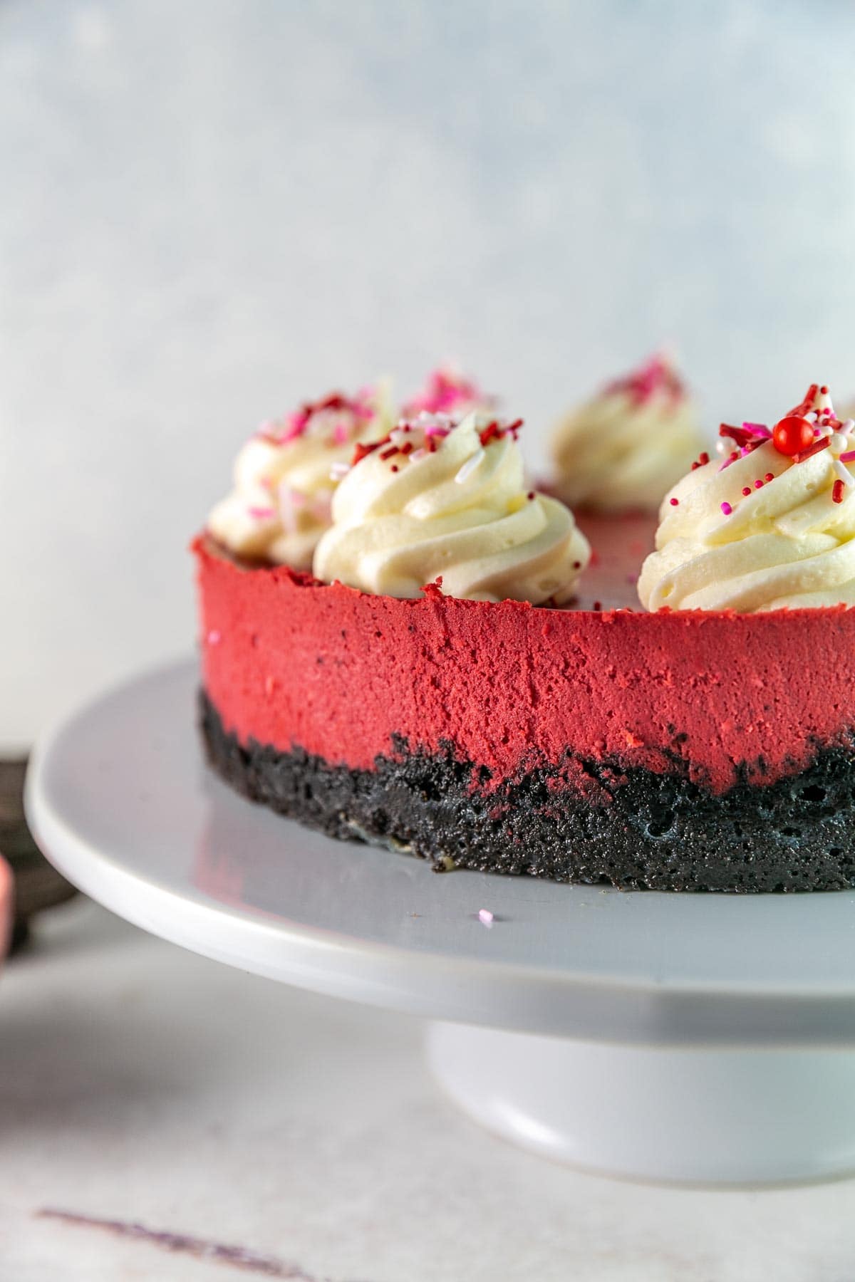 side view of red velvet cheesecake showing the oreo crust and deep red cheesecake