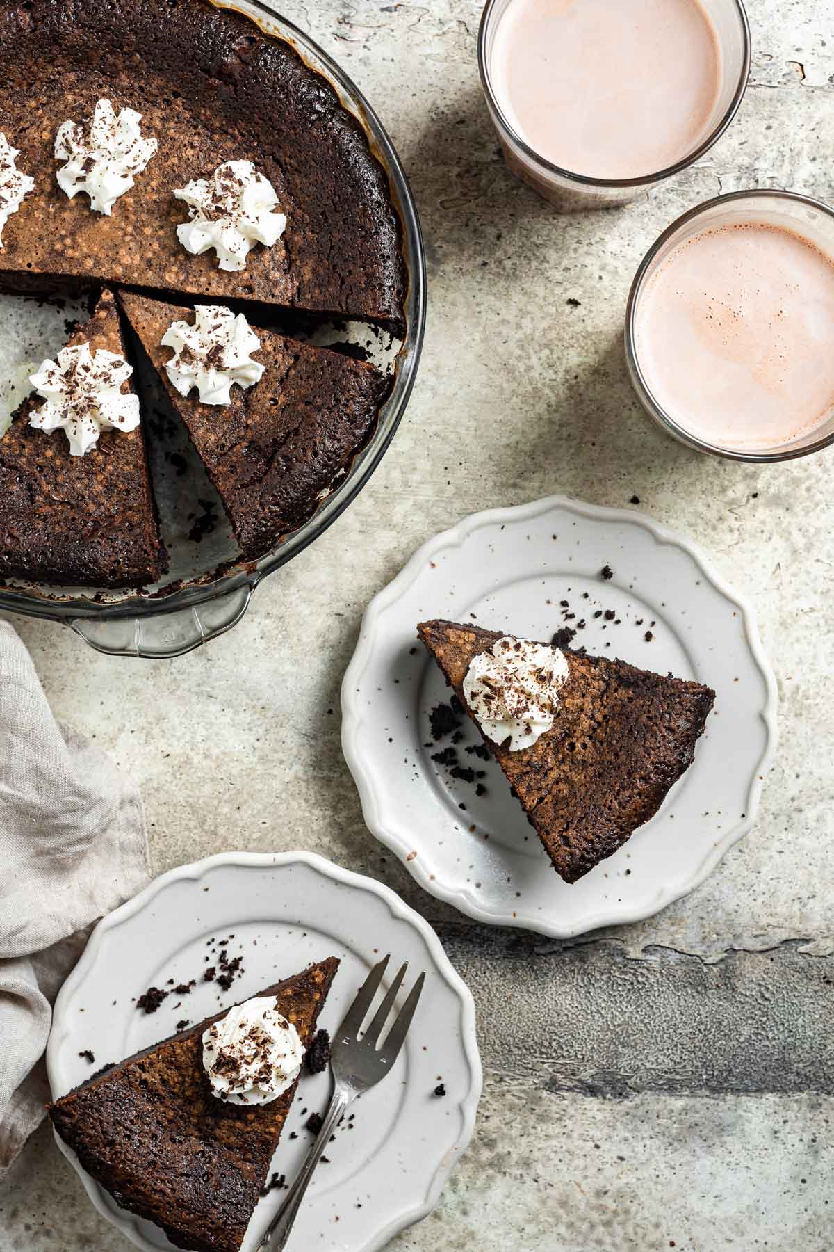 two slices of buttermilk pie topped with whipped cream on white dessert plates