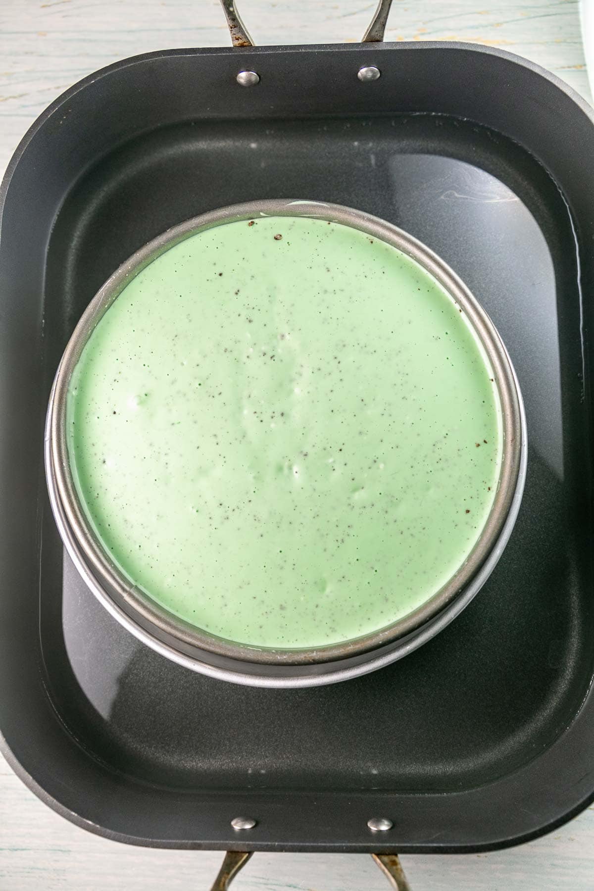 unbaked green cheesecake in a water bath