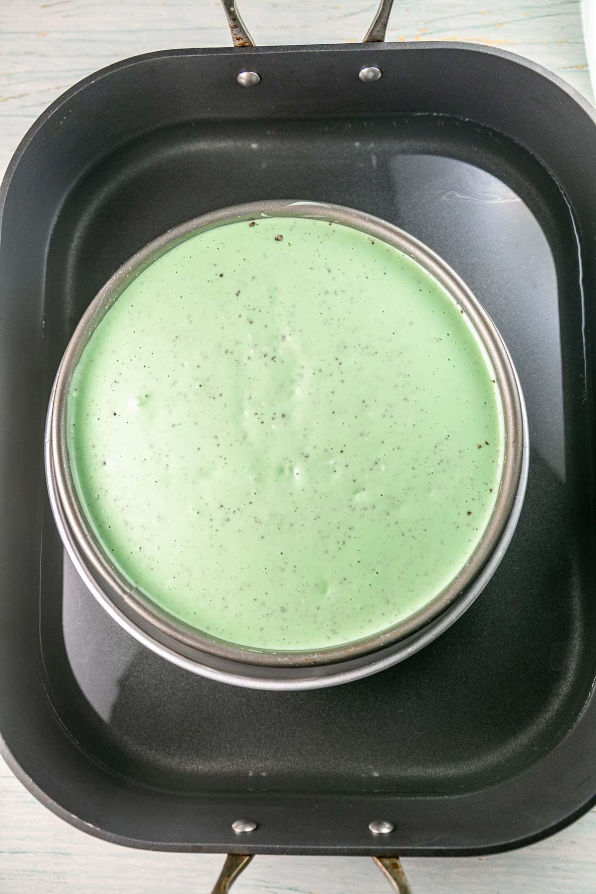 unbaked green cheesecake in a water bath.