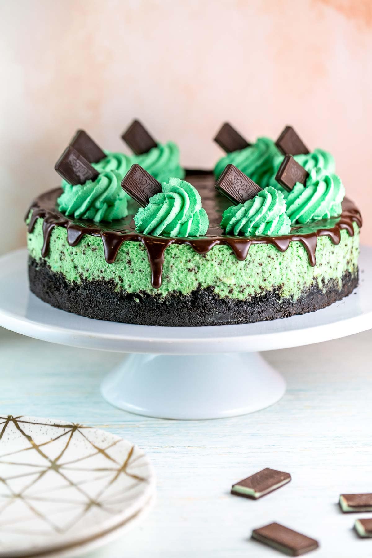 mint chocolate cheesecake with oreo crust on a white cake plate.