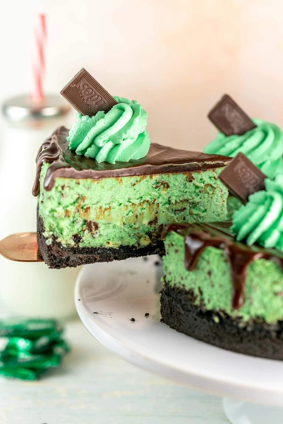 cake server lifting one slice of mint chocolate cheesecake away from the whole cheesecake.