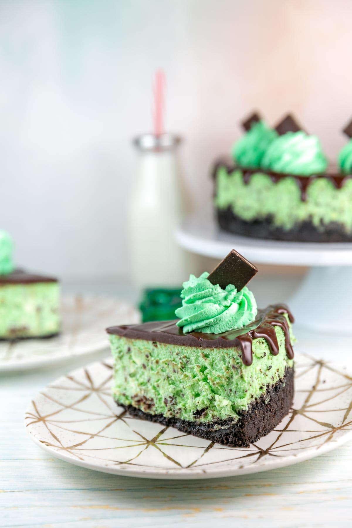 slice of Andes mint cheesecake with chocolate ganache on a decorative gold plate.