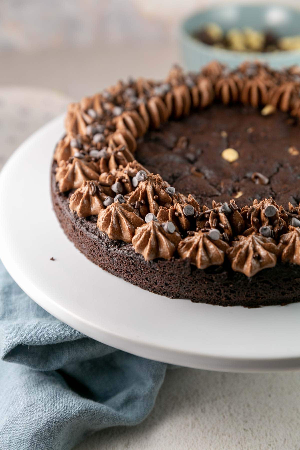 thick dark chocolate cookie cake with piped frosting and chocolate chips