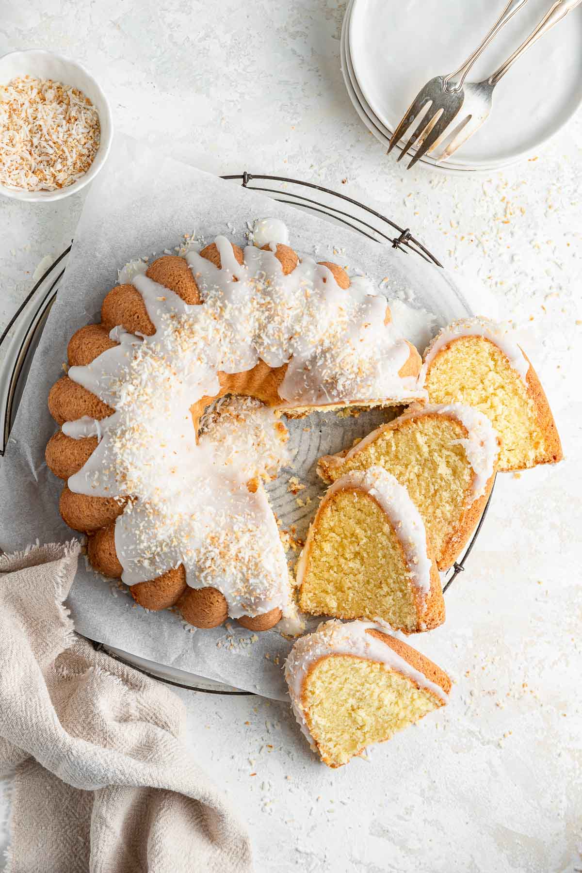 bundt cake covered with shredded coconut with four slices lined up next to the cake