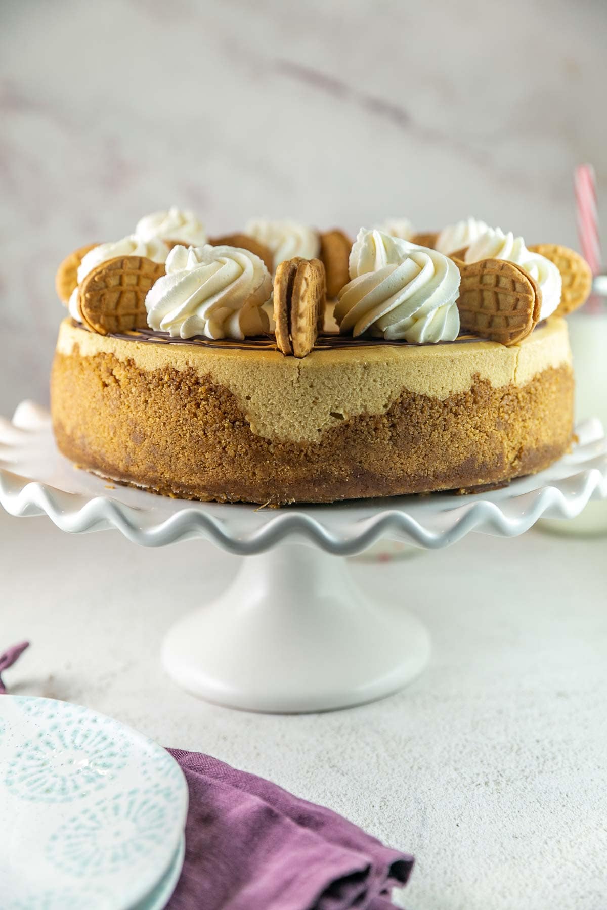 side view of a whole cheesecake decorated with whipped cream and nutter butters