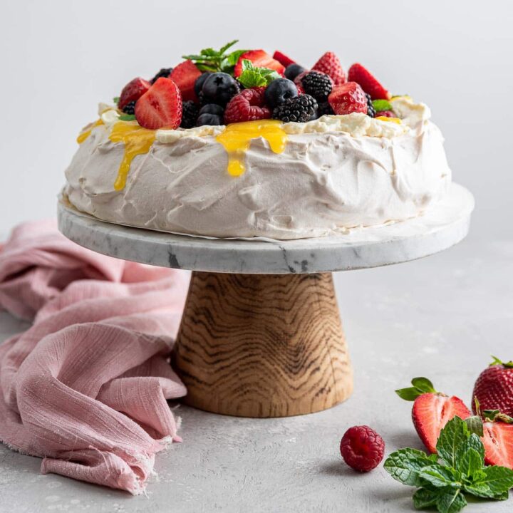 sky high pavlova piled with berries and lemon curd