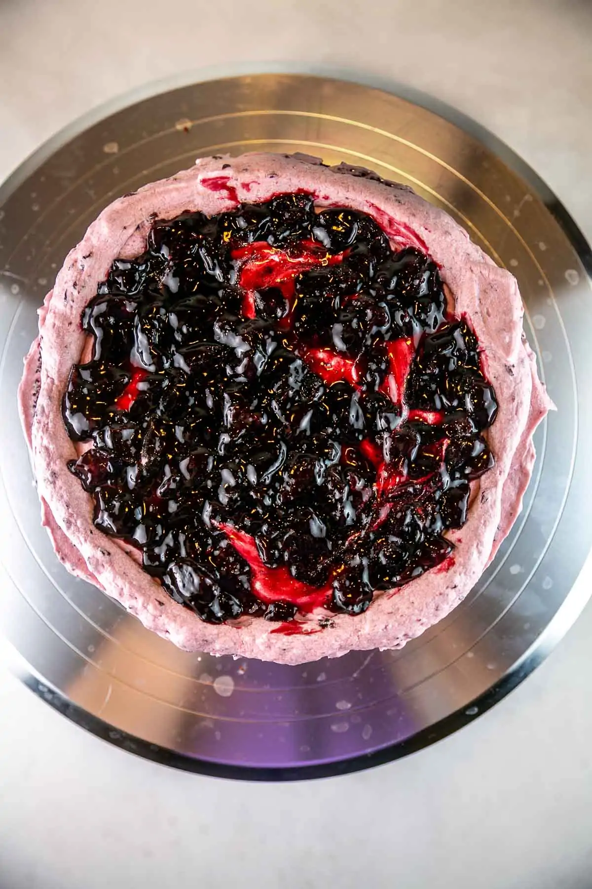overhead view of a cake layer covered with buttercream and filled with cherries