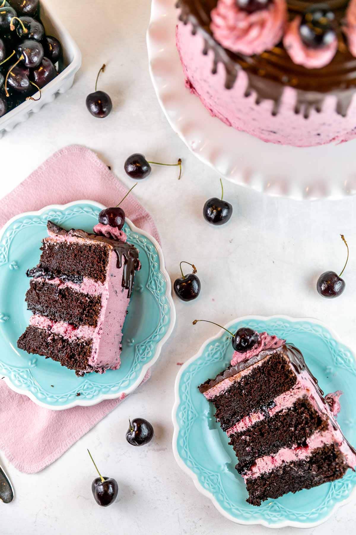 two slices of cherry chocolate cake on bright blue dessert plates