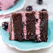 slice of three layer chocolate cake filled with cherries