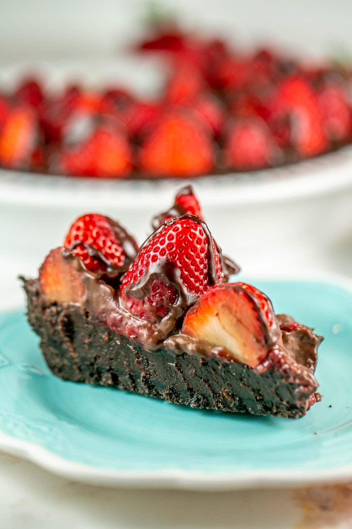 Slice of chocolate pie topped with strawberries on a plate. 