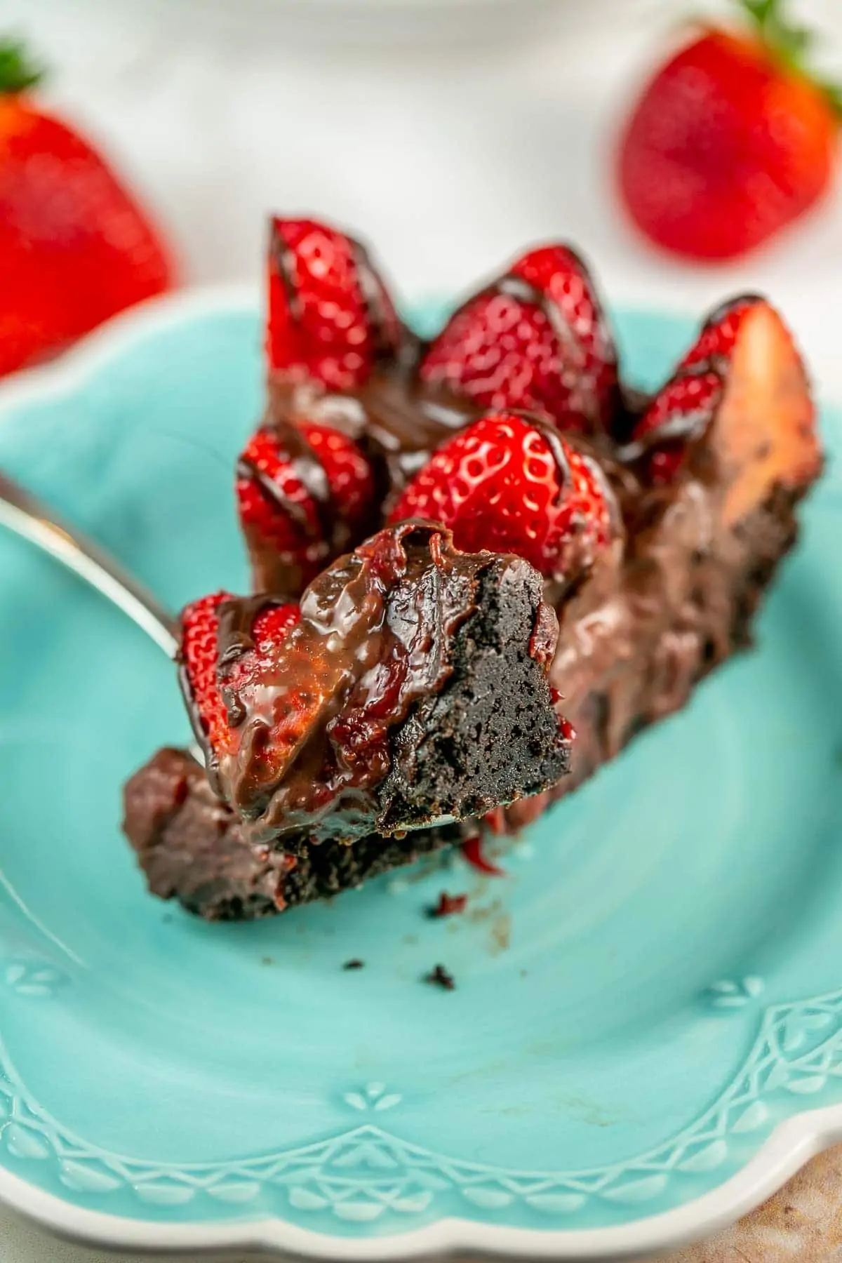 Slice of pie with strawberries on top and a fork on a plate.