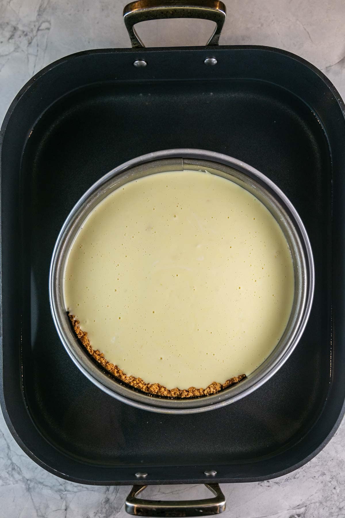Unbaked cheesecake in a water bath before going into the oven.