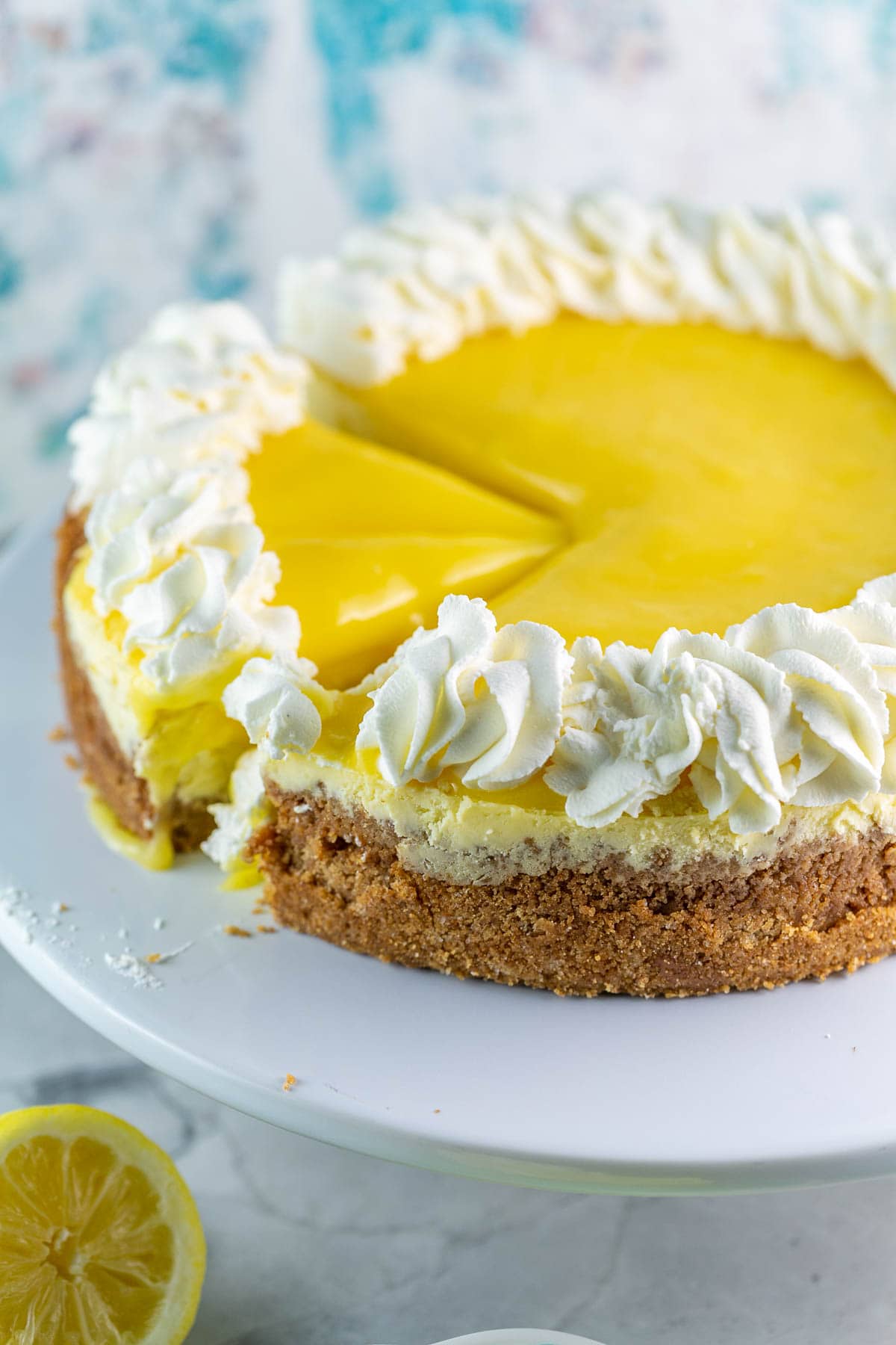 Lemon curd cheesecake on a cake stand with two pieces cut. 