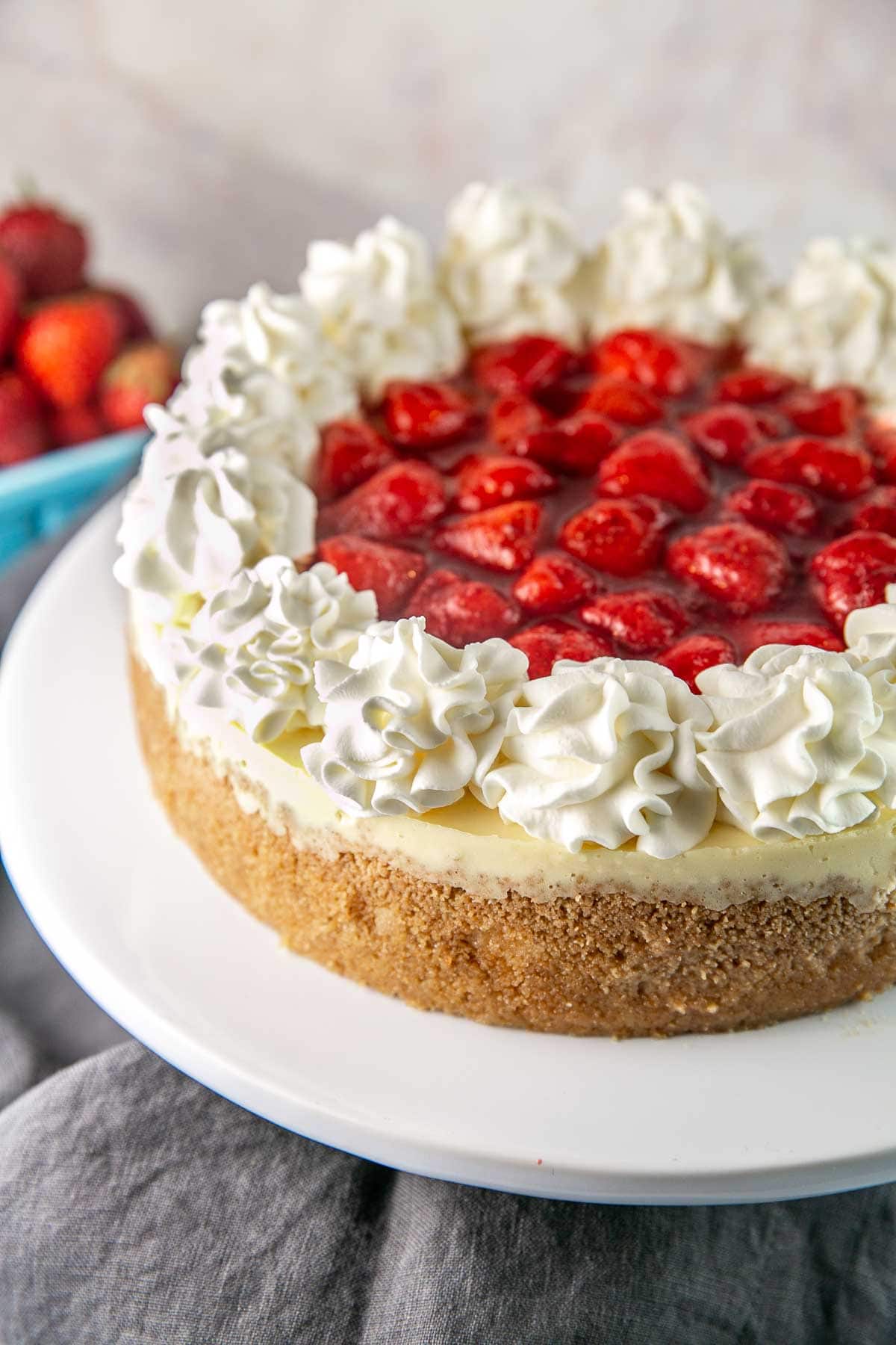 whole cheesecake covered with strawberries, strawberry sauce, and whipped cream