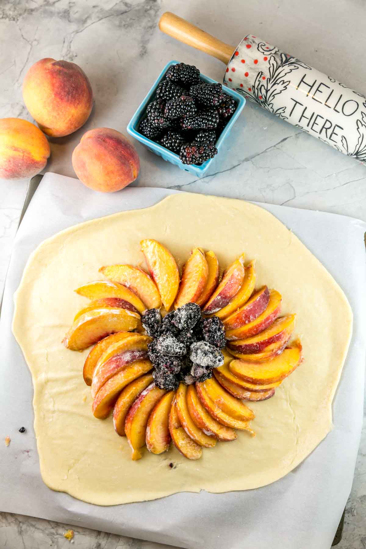 rolled out dough with peaches and blackberries arranged in the center