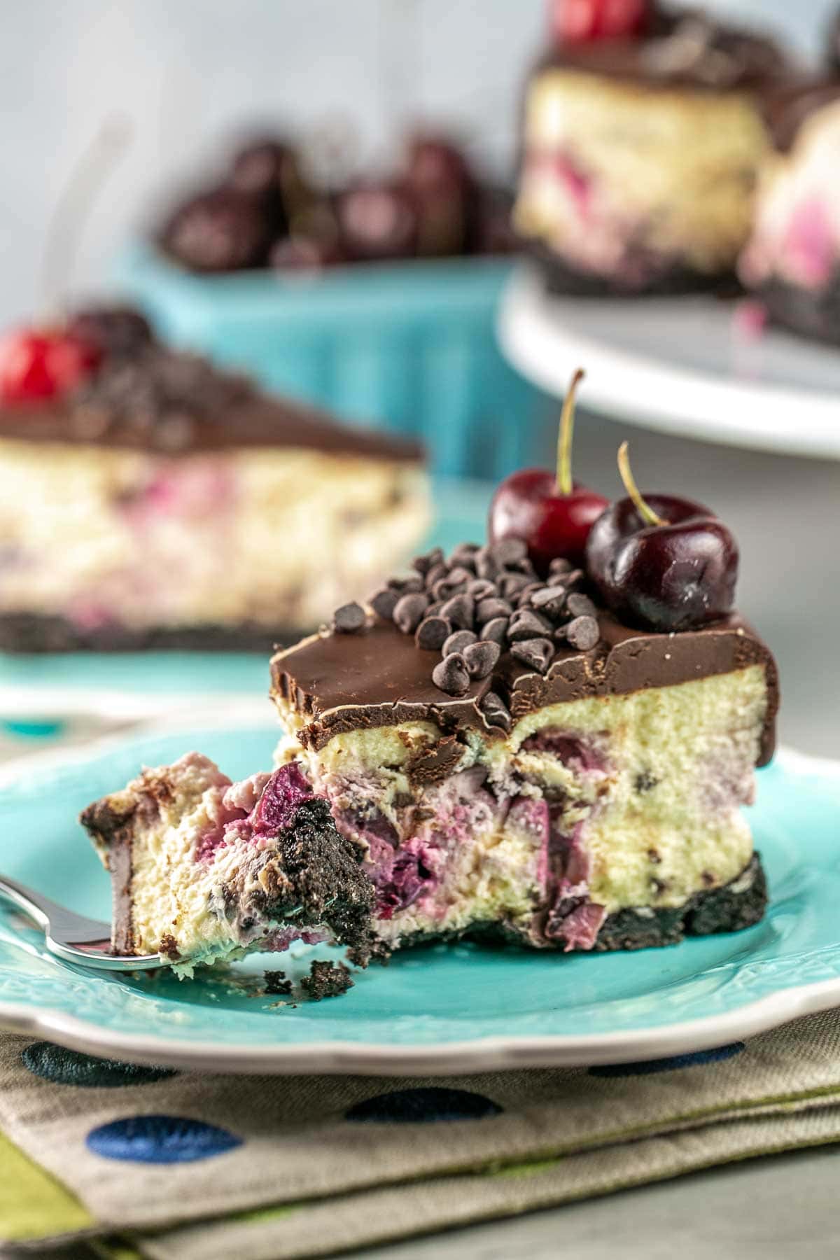 chocolate chip cherry cheesecake with a bite of the cheesecake on a fork