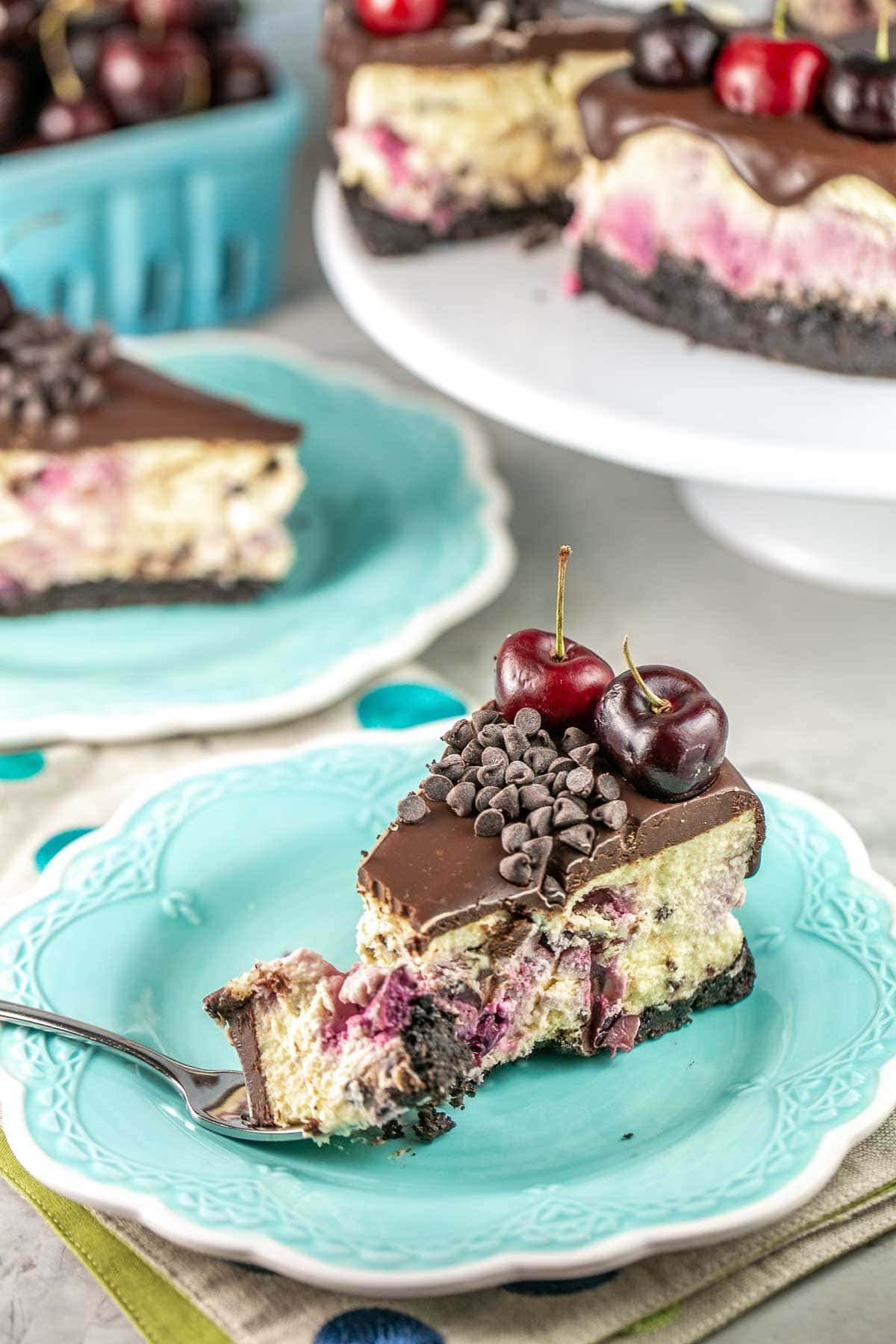 slice of cheesecake topped with ganache and fresh cherries