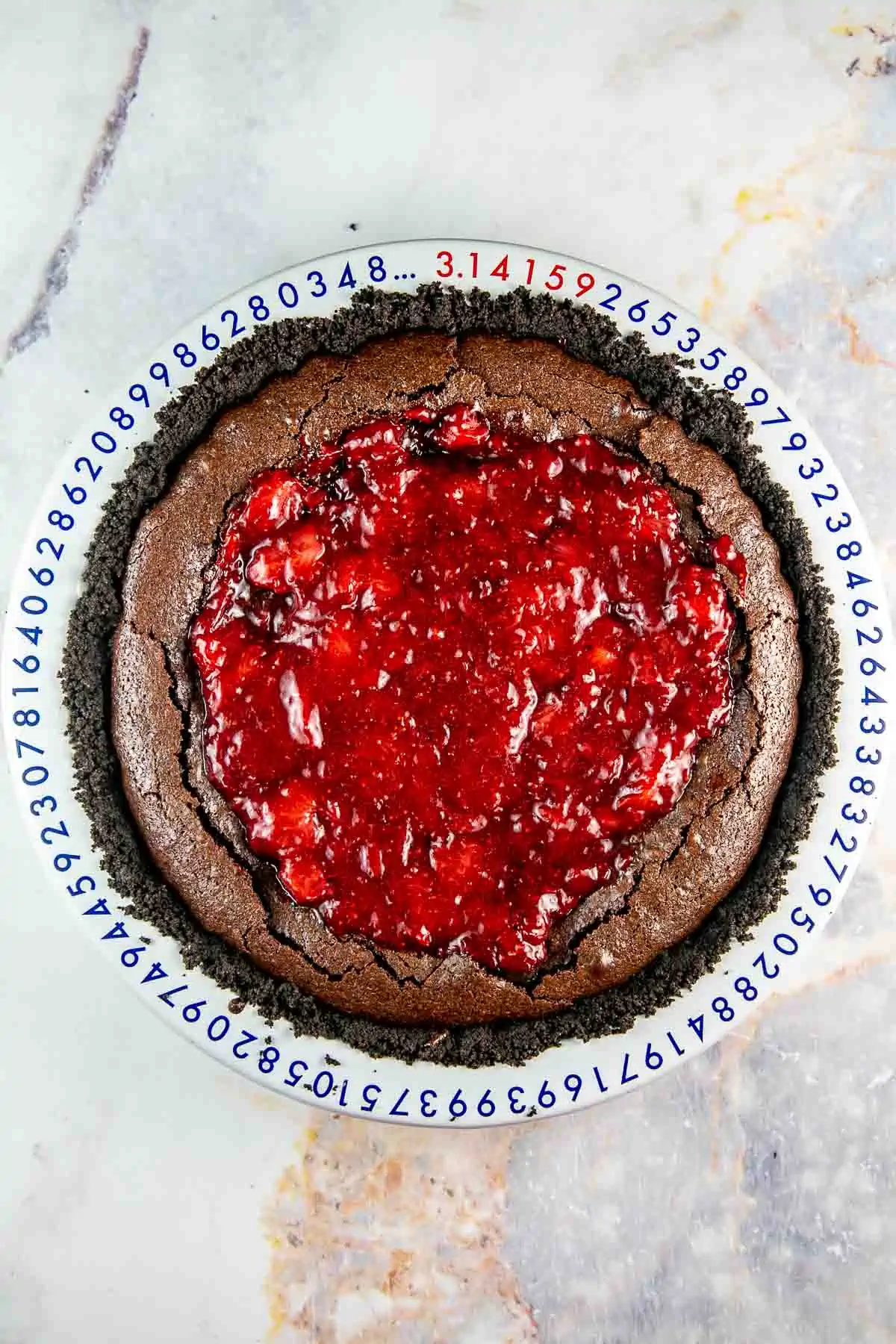 Pie pan with brownie filling and strawberry jam on top.