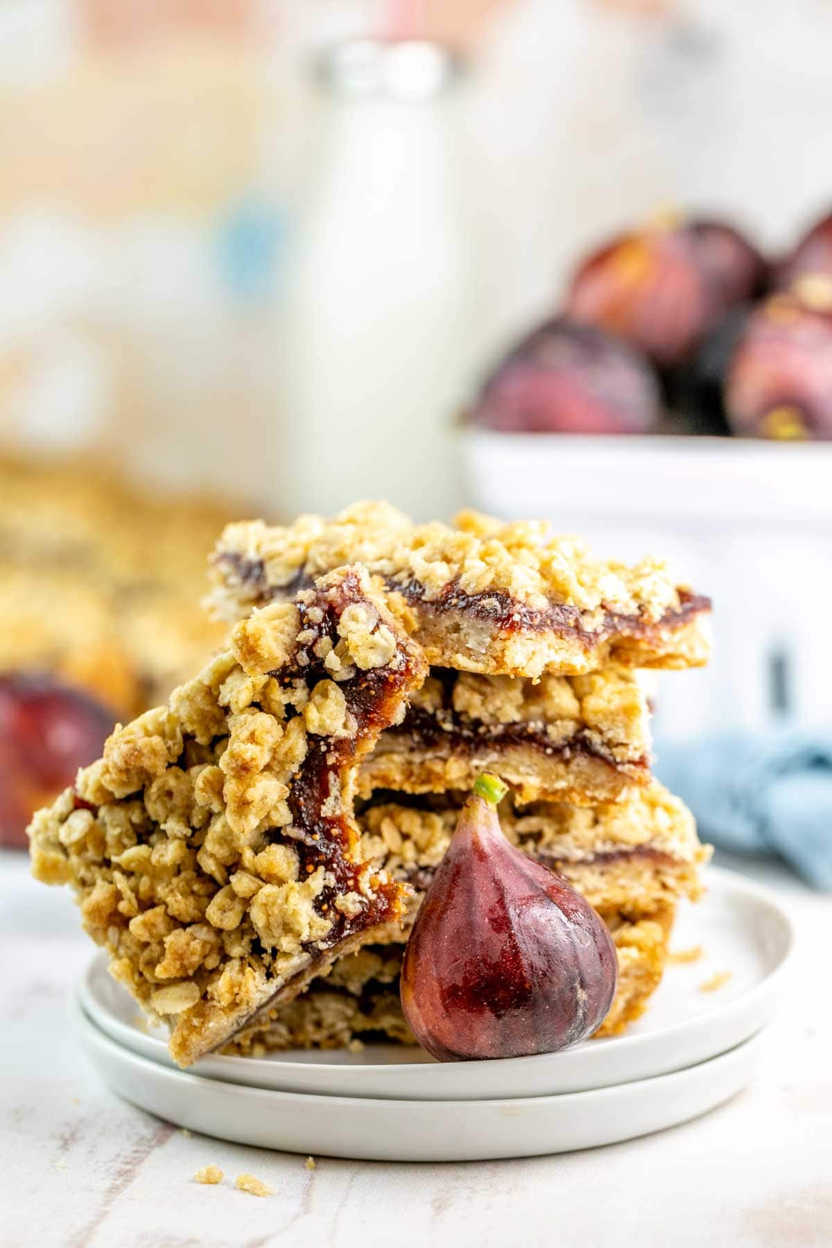 Fig bars stacked on a white plate with a bite out of the top fig bar. 