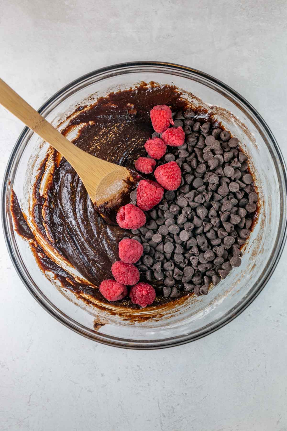 Brownie ingredients being mixed in a bowl with a wooden spoon. 