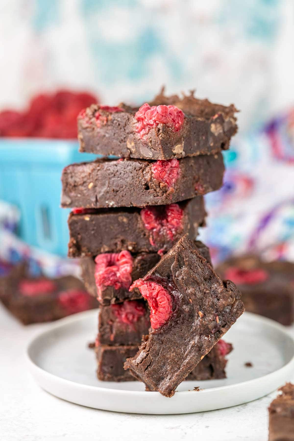 Brownies stacked on a plate with one brownie missing a bite. 