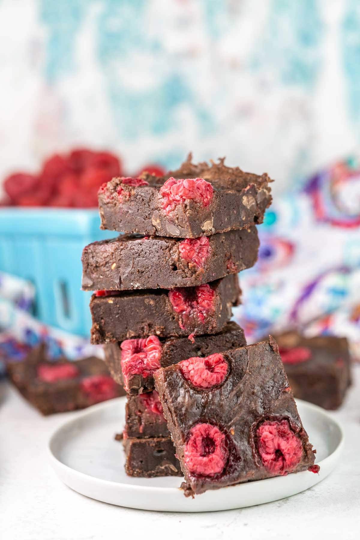 Raspberry brownies stacked on a plate.