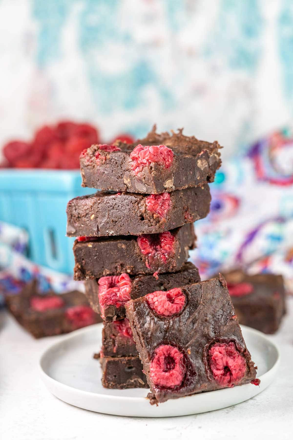 Raspberry brownies stacked on a plate. 