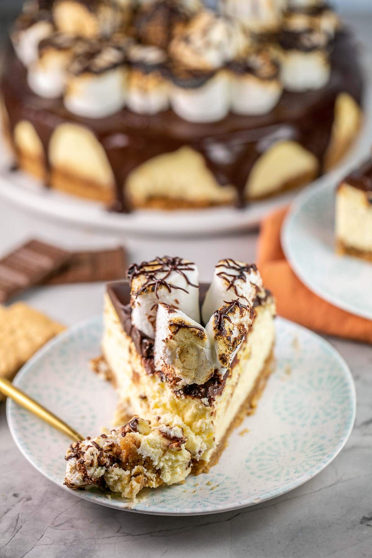 piece of cheesecake on a plate with one bite on a gold fork