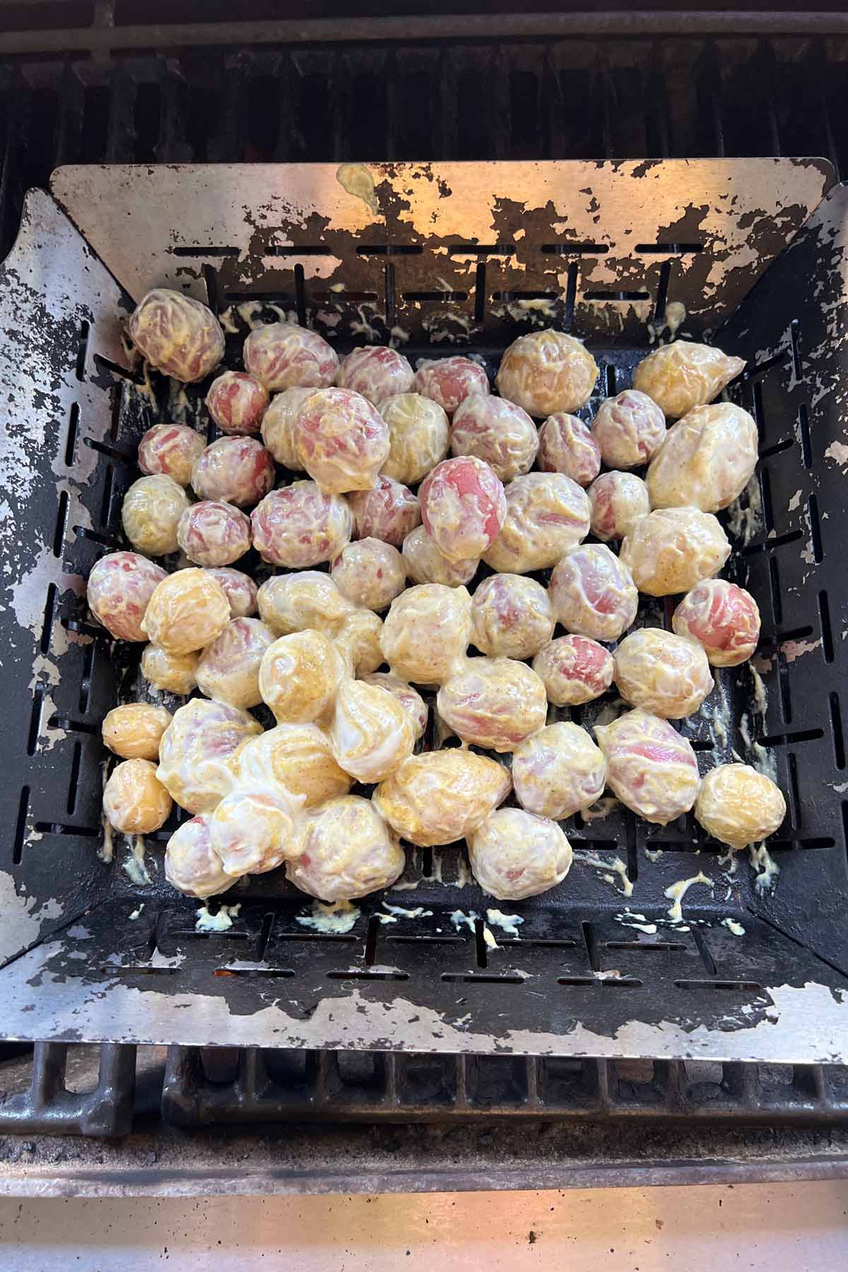 small potatoes covered with mustard in a grill basket