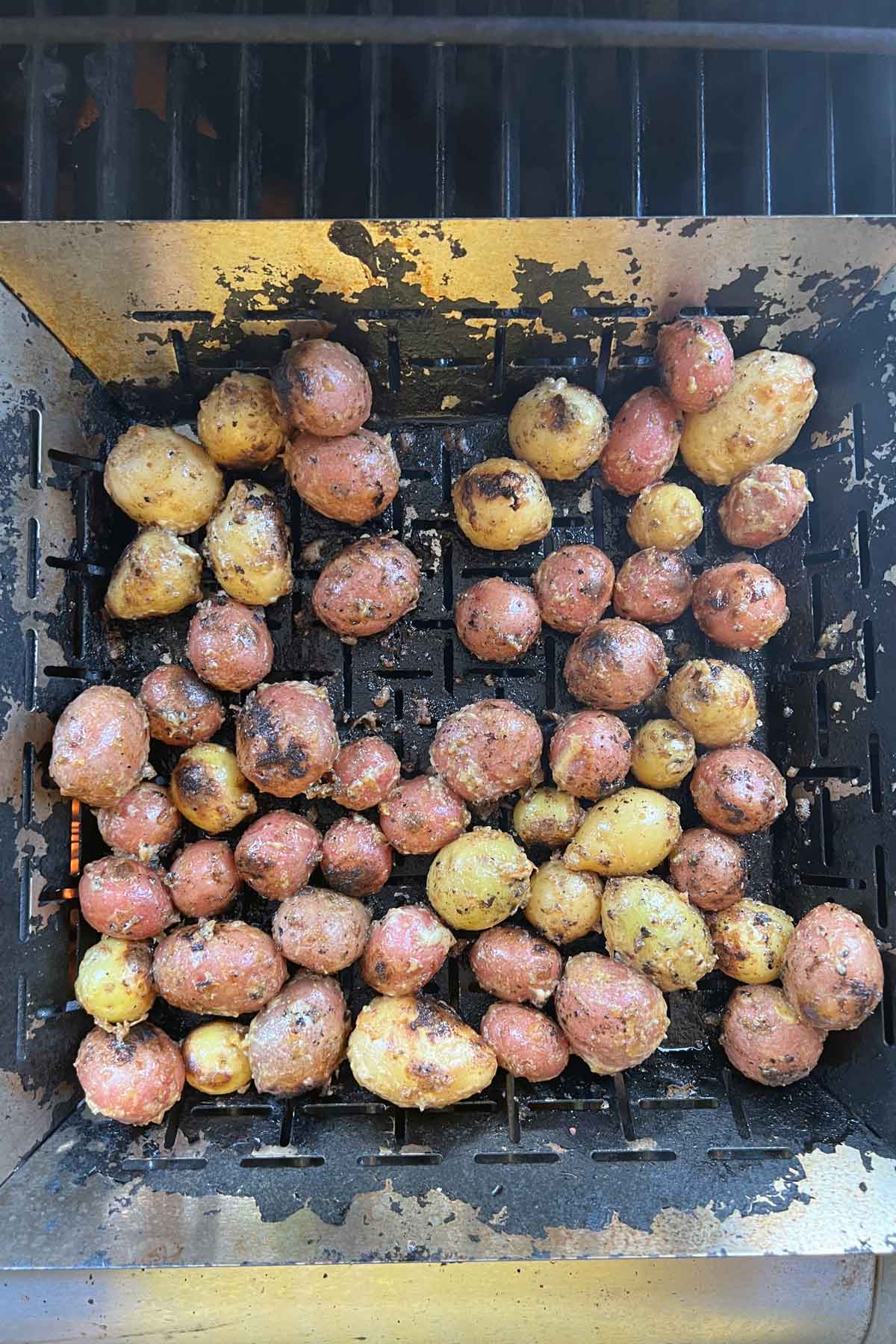 potatoes in a grill basket starting to char and darken