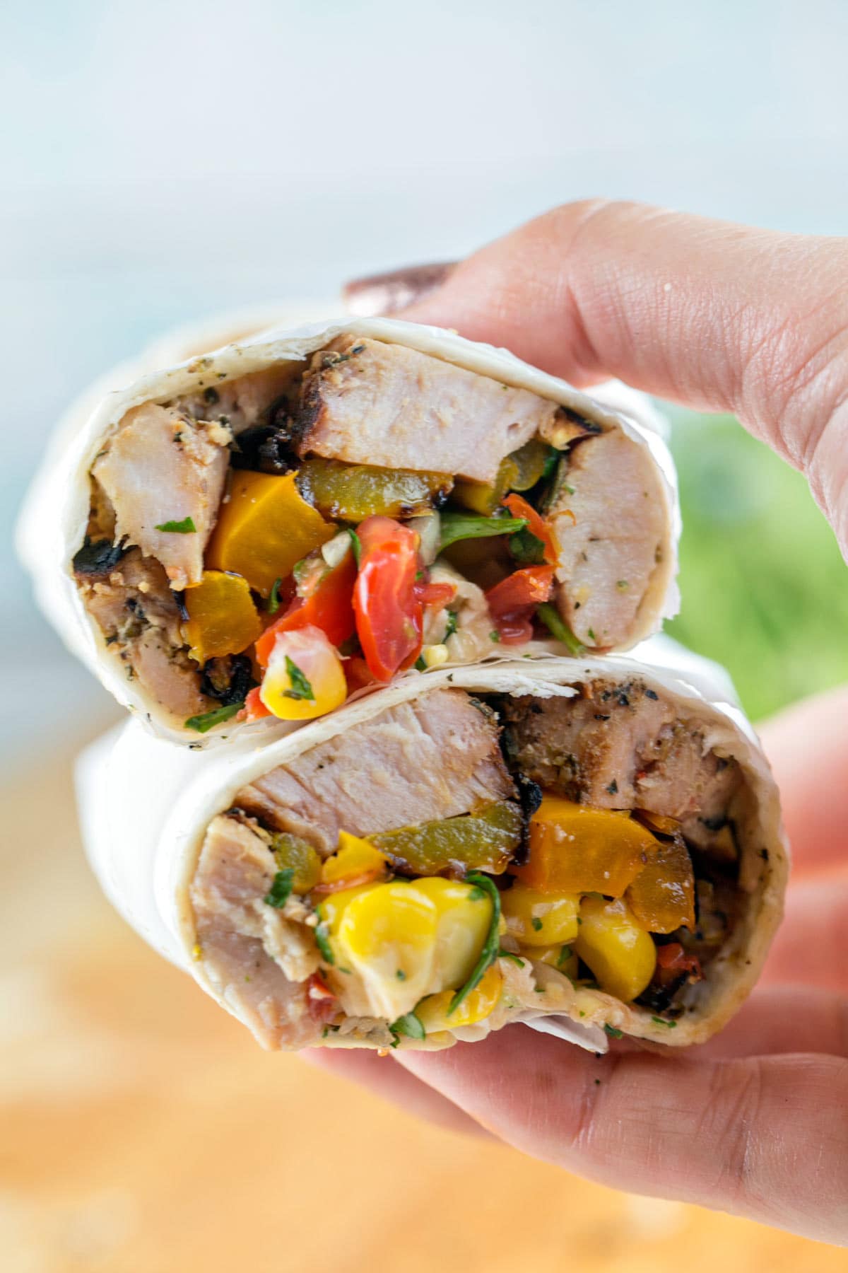 hand holding two halves of a wrap showing the pork and vegetables inside
