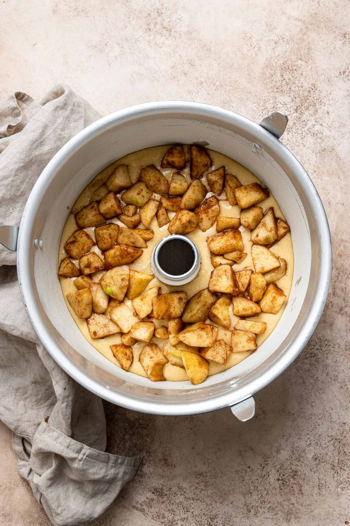 layer of cake batter and cinnamon apples in a tube pan