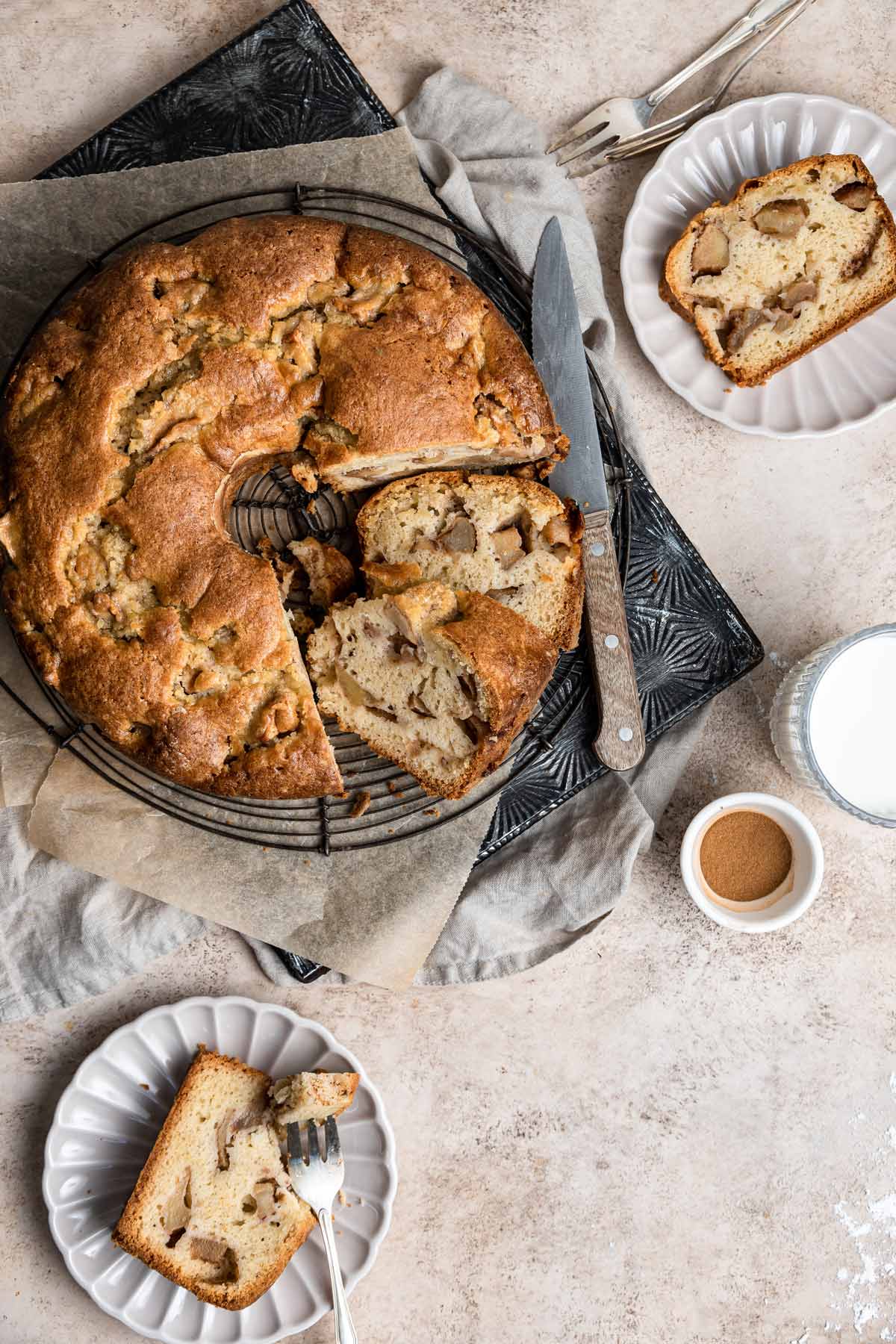 overhead view of an apple cake with two slices on dessert plates