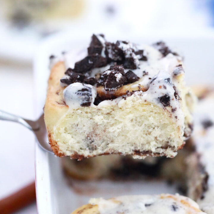 oreo cinnamon roll being lifted out of the pan on a spatula