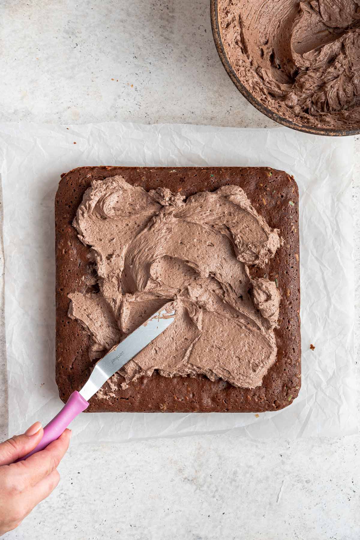 spreading chocolate frosting on brownies with an offset spatula