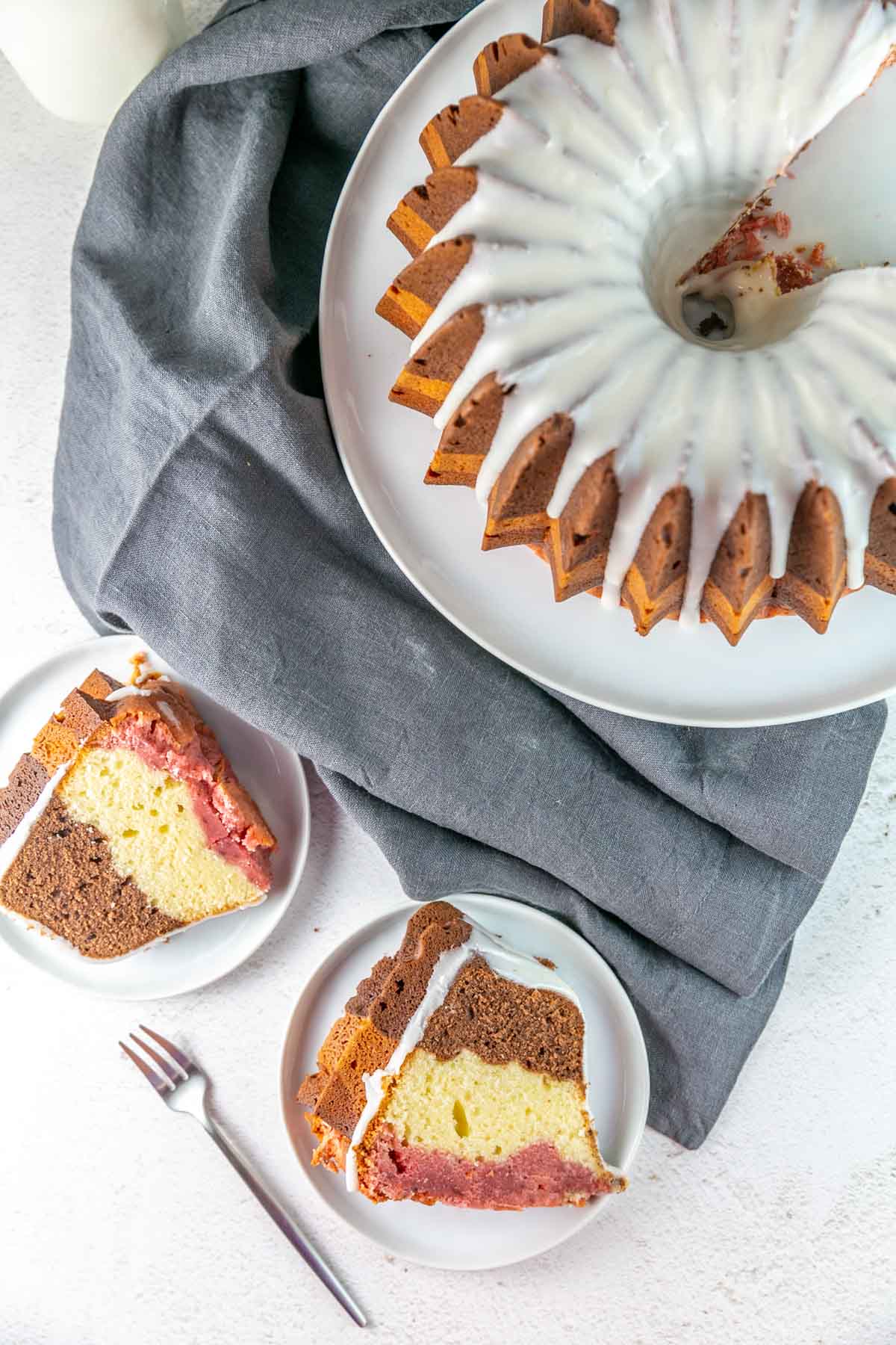 Top view of cake on a cake stand with two slices of cake on white plates next to it.