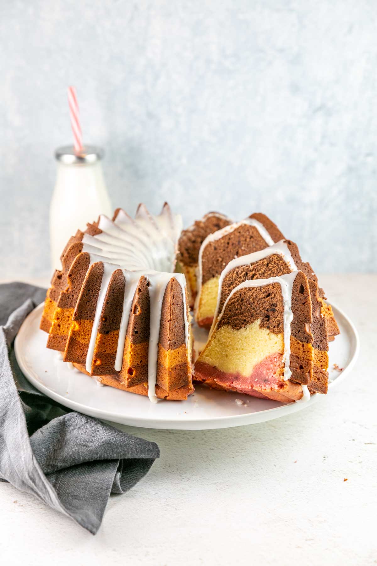 Neapolitan bundt cake on a white cake stand with half of the cake in separated slices.