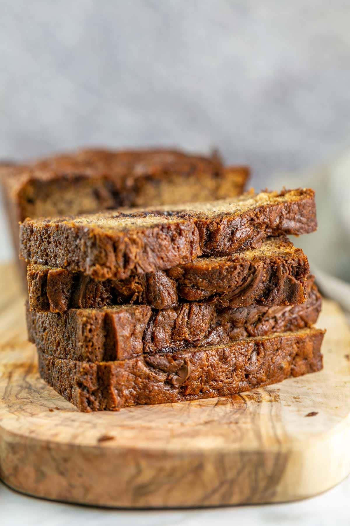 Stacks of sliced banana bread on a wooden cutting board. 