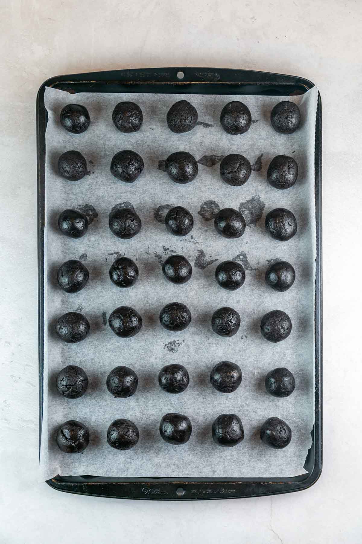 uncoated oreo truffles lined up on a cookie sheet