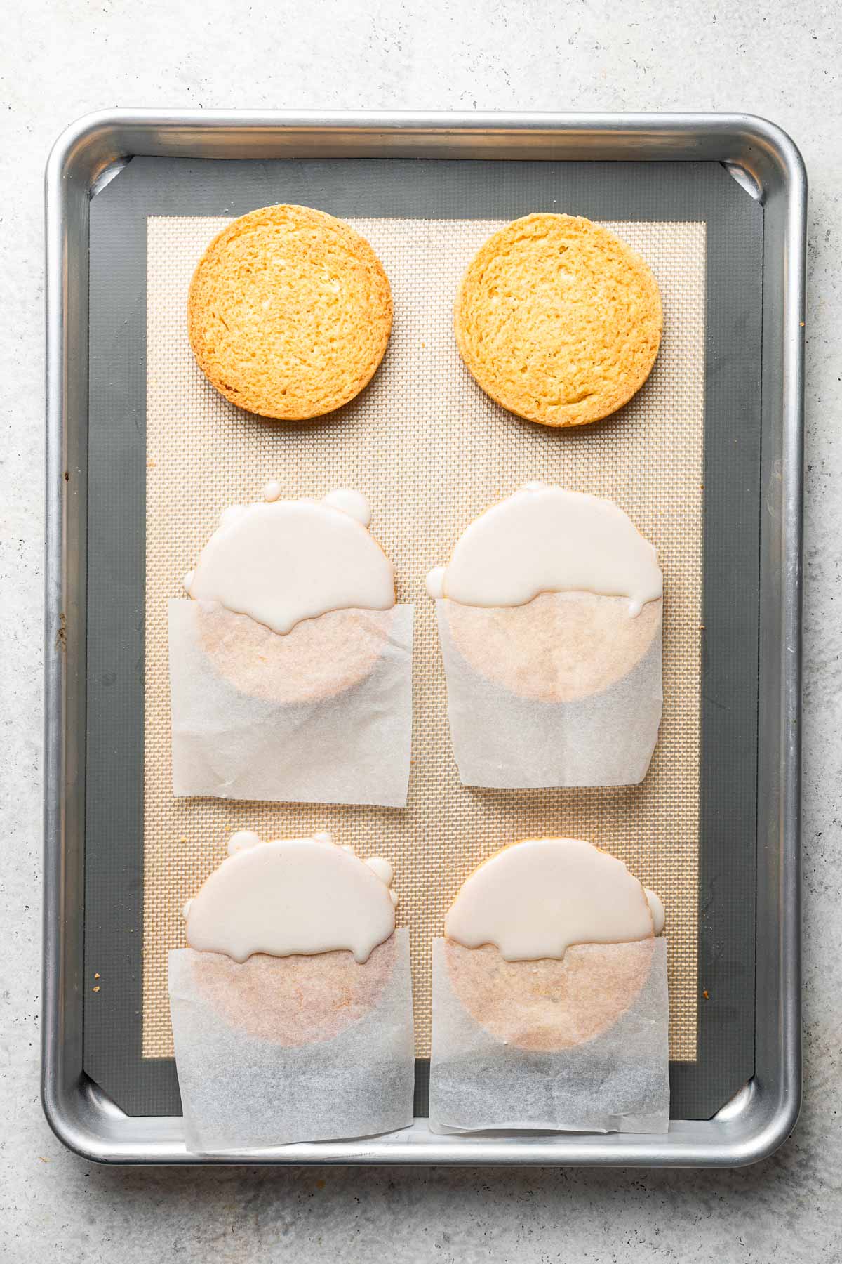 squares of wax paper covering half the cookie for a smooth line between chocolate and vanilla frosting